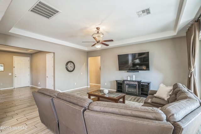 3022 S Open Range Way, Tucson, AZ 85713 - living room with a raised ceiling, a ceiling fan, baseboards, and light wood-style floors
