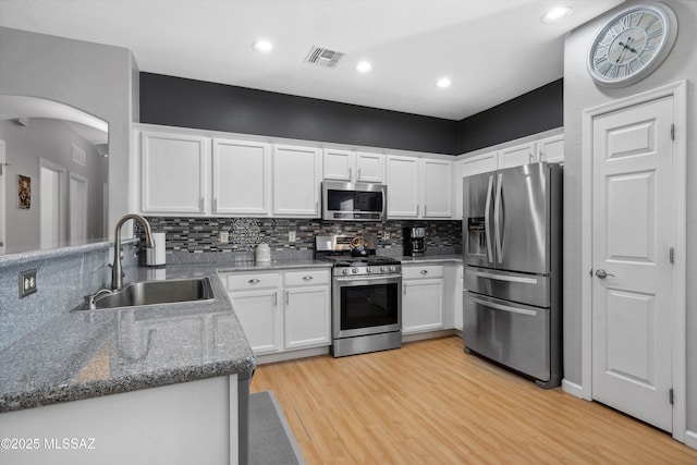 14511 S Camino Tierra Luna, Sahuarita, AZ 85629 - kitchen with stainless steel appliances, a sink, light wood finished floors, arched walkways, and white cabinets