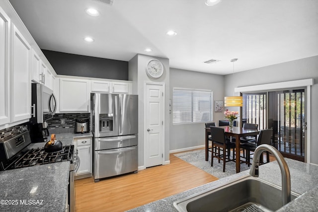 14511 S Camino Tierra Luna, Sahuarita, AZ 85629 - kitchen with appliances with stainless steel finishes, a sink, white cabinets, light wood finished floors, and backsplash