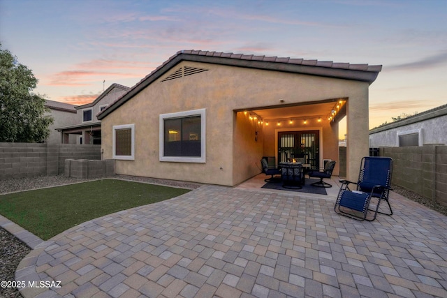 14511 S Camino Tierra Luna, Sahuarita, AZ 85629 - back of house at dusk featuring a patio area, a fenced backyard, stucco siding, and an outdoor fire pit