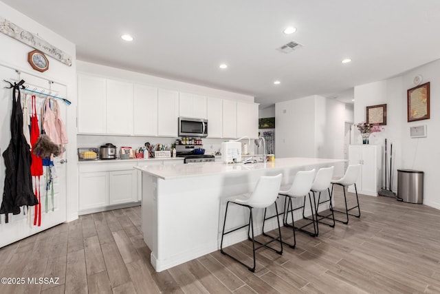 5568 W Summer Vw Dr, Marana, AZ 85658 - kitchen with appliances with stainless steel finishes, a kitchen island with sink, light wood-type flooring, white cabinets, and recessed lighting