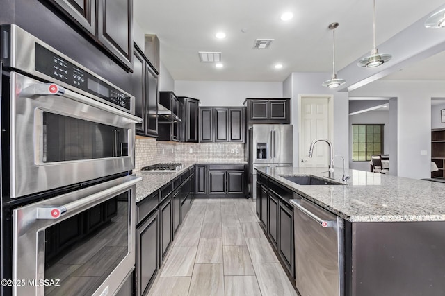 11874 N Raphael Way, Tucson, AZ 85742 - kitchen featuring a sink, stainless steel appliances, a center island with sink, backsplash, and light stone countertops