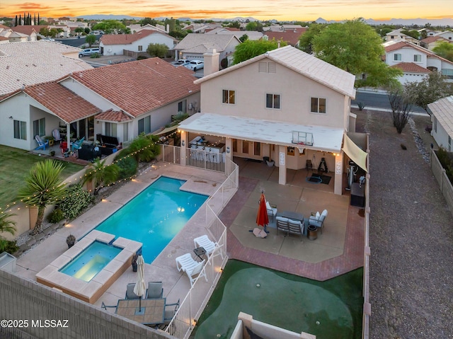 9880 E Cisco Ct, Tucson, AZ 85748 - pool at dusk with a fenced backyard, a residential view, a patio area, and a pool with connected hot tub