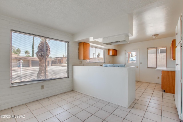 9552 E Irene St, Tucson, AZ 85730 - kitchen featuring light countertops, light tile patterned floors, a peninsula, a textured ceiling, and brown cabinets