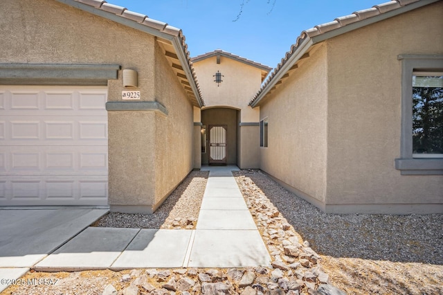 9225 S Summer Breeze Ln, Tucson, AZ 85756 - view of exterior entry featuring stucco siding, a garage, a tile roof, and a gate