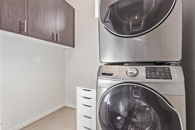 890 E Millenium Ct Unit E, Tucson, AZ 85719 - washroom featuring cabinet space, stacked washer and clothes dryer, light tile patterned floors, and baseboards