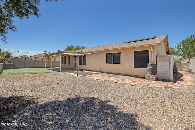 7925 S Danforth Ave, Tucson, AZ 85747 - rear view of property with a fenced backyard, roof mounted solar panels, a patio area, stucco siding, and roof with shingles