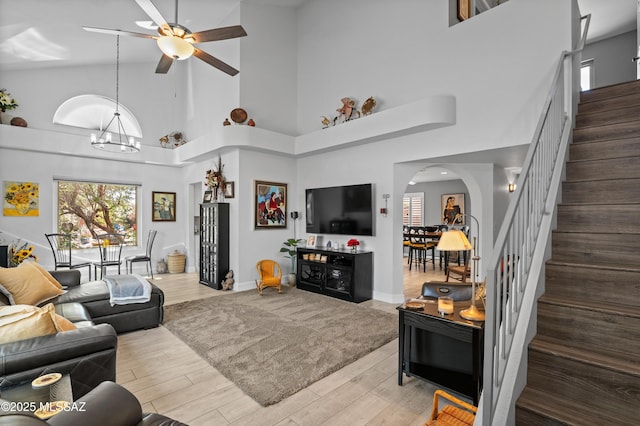 9000 N Twain St, Tucson, AZ 85742 - living room featuring arched walkways, stairway, a high ceiling, a ceiling fan, and wood finished floors