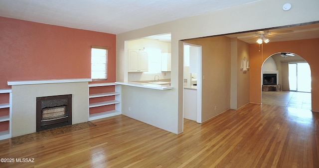 2422 E Drachman St, Tucson, AZ 85719 - unfurnished living room with a fireplace with flush hearth, arched walkways, ceiling fan, and light wood-style floors