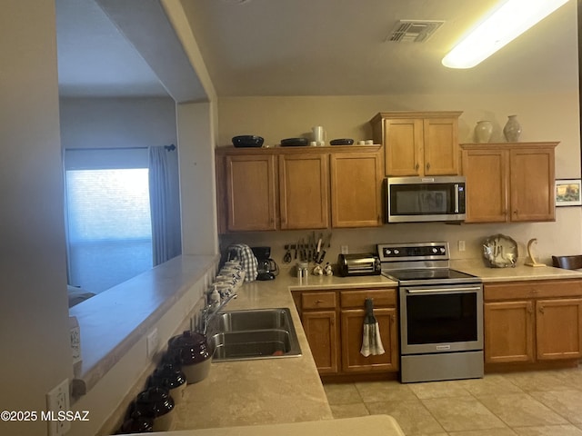 15808 S Via Cayetano, Sahuarita, AZ 85629 - kitchen featuring stainless steel appliances, light countertops, a sink, light tile patterned flooring, and brown cabinets