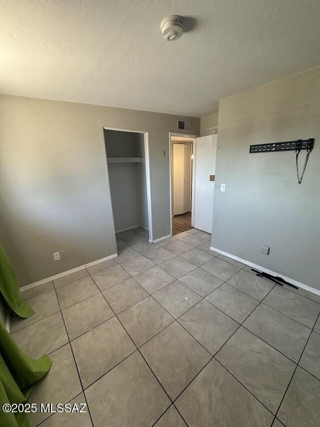 3958 N Pomona Rd, Tucson, AZ 85705 - unfurnished bedroom featuring a textured ceiling, baseboards, light tile patterned floors, and a closet