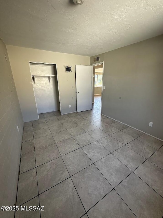 3958 N Pomona Rd, Tucson, AZ 85705 - unfurnished bedroom featuring a closet, light tile patterned floors, a textured ceiling, and baseboards