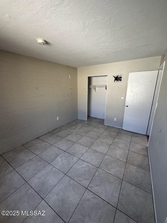 3958 N Pomona Rd, Tucson, AZ 85705 - unfurnished room with a textured ceiling, concrete block wall, a smoke detector, and light tile patterned flooring