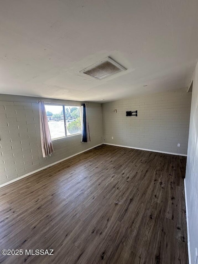 3958 N Pomona Rd, Tucson, AZ 85705 - unfurnished room with attic access, dark wood-style flooring, brick wall, and baseboards