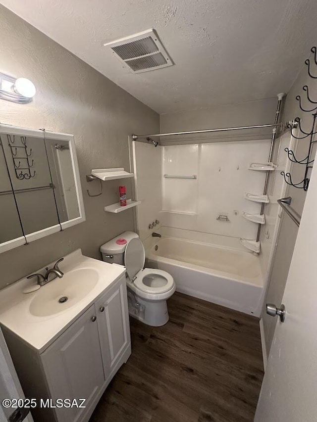 3958 N Pomona Rd, Tucson, AZ 85705 - bathroom featuring wood finished floors, vanity, tub / shower combination, toilet, and a textured wall