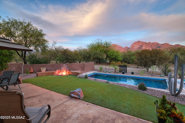 10550 N Lambert Pl, Tucson, AZ 85737 - pool at dusk featuring an outdoor fire pit, a patio, and a mountain view