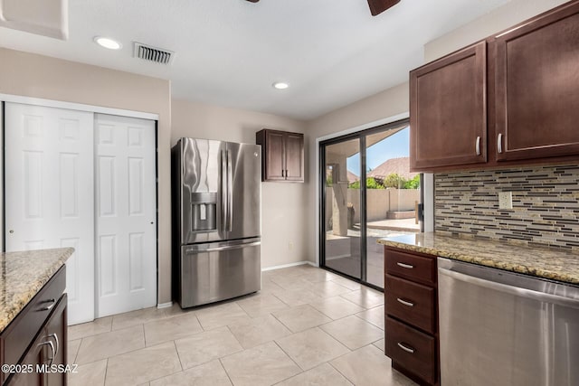 231 E Highcourte Ln, Tucson, AZ 85737 - kitchen with appliances with stainless steel finishes, decorative backsplash, dark brown cabinets, light stone counters, and baseboards