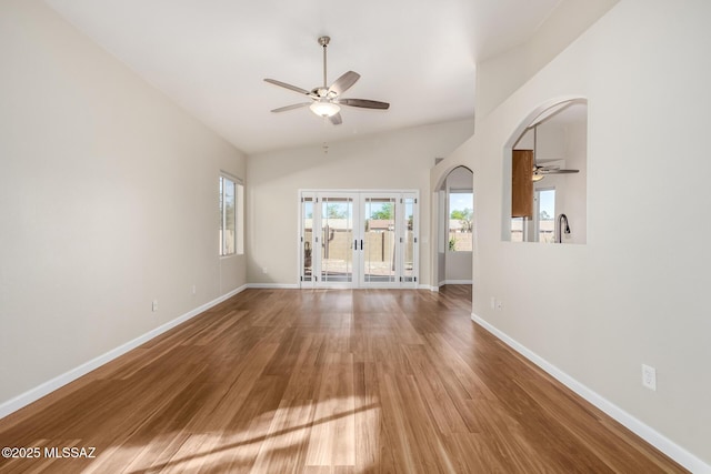 9102 N Safflower Ln, Tucson, AZ 85743 - unfurnished living room with a ceiling fan, arched walkways, wood finished floors, baseboards, and french doors