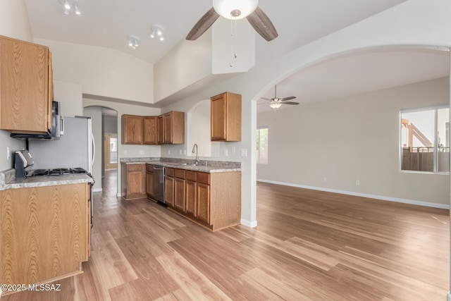 9102 N Safflower Ln, Tucson, AZ 85743 - kitchen with arched walkways, a ceiling fan, stainless steel appliances, open floor plan, and light wood finished floors