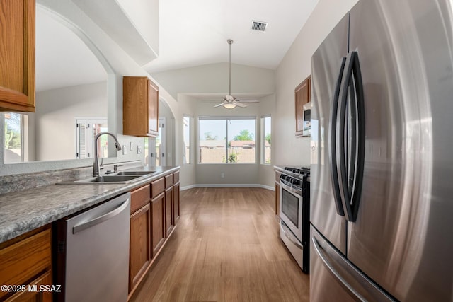 9102 N Safflower Ln, Tucson, AZ 85743 - kitchen featuring stainless steel appliances, a sink, brown cabinets, light wood finished floors, and arched walkways