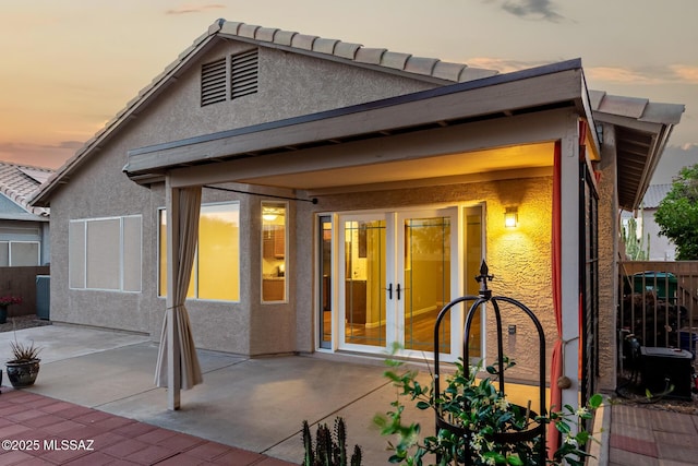 9102 N Safflower Ln, Tucson, AZ 85743 - back of house at dusk featuring french doors, stucco siding, and a patio area
