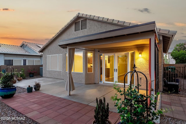 9102 N Safflower Ln, Tucson, AZ 85743 - back of property at dusk featuring french doors, stucco siding, a patio area, and a fenced backyard