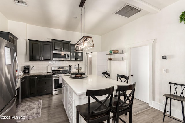 118 N Hoff Ave, Tucson, AZ 85705 - kitchen featuring appliances with stainless steel finishes, a breakfast bar area, decorative backsplash, light countertops, and light wood-type flooring