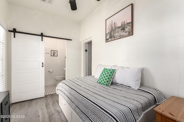 118 N Hoff Ave, Tucson, AZ 85705 - bedroom with a barn door, light wood-style floors, ensuite bath, and ceiling fan