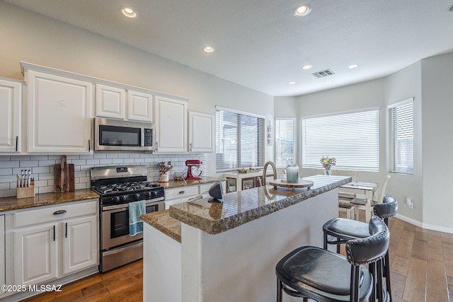 983 N Via Zahara Del Sol, Tucson, AZ 85748 - kitchen featuring stainless steel appliances, a breakfast bar area, wood finished floors, decorative backsplash, and white cabinetry