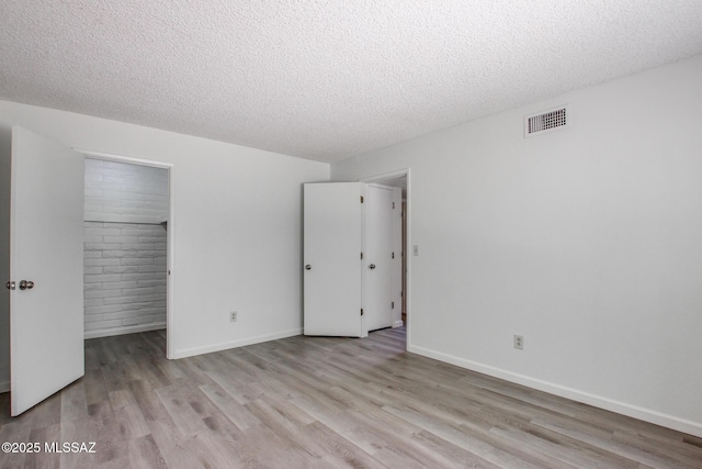 8450 E Old Spanish Trl Unit 157, Tucson, AZ 85710 - unfurnished bedroom with wood finished floors, a textured ceiling, a spacious closet, a closet, and baseboards