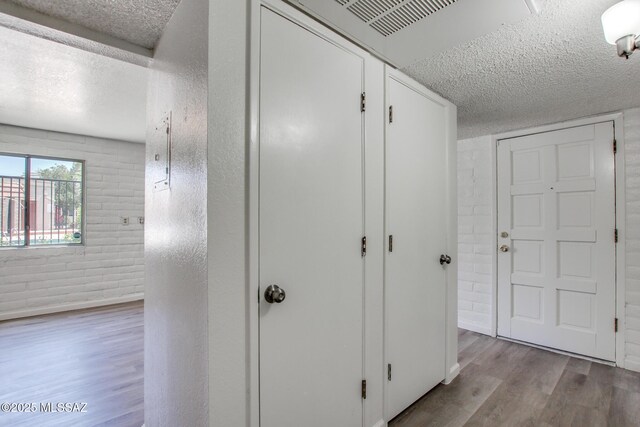 8450 E Old Spanish Trl Unit 157, Tucson, AZ 85710 - hallway with a textured ceiling, wood finished floors, and brick wall
