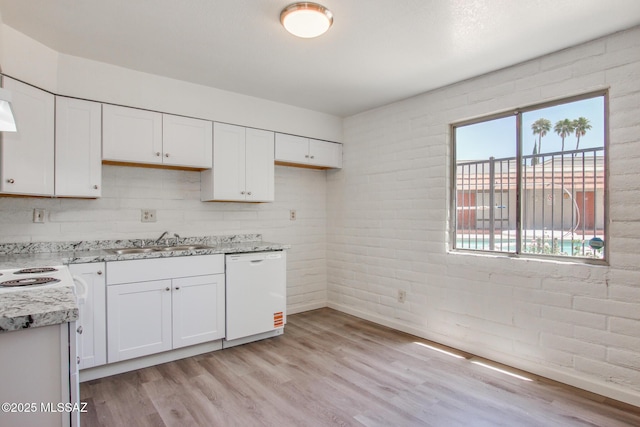 8450 E Old Spanish Trl Unit 157, Tucson, AZ 85710 - kitchen featuring dishwasher, a sink, light wood-type flooring, white cabinets, and brick wall