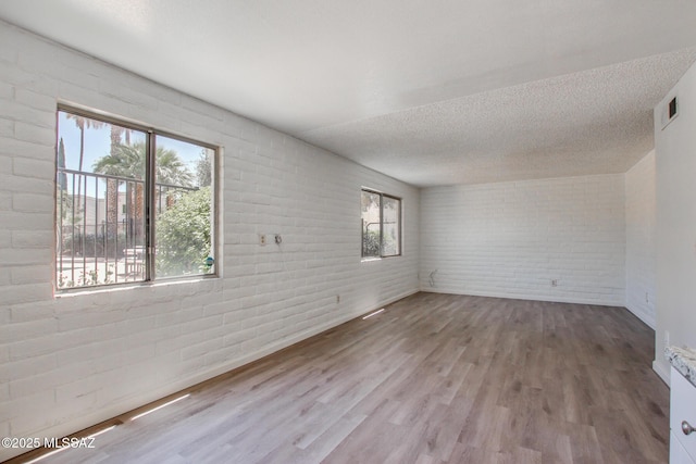 8450 E Old Spanish Trl Unit 157, Tucson, AZ 85710 - unfurnished room featuring healthy amount of natural light, brick wall, wood finished floors, a textured ceiling, and baseboards
