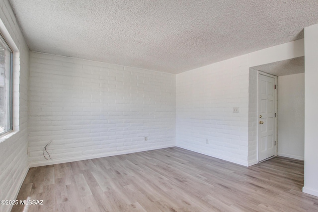 8450 E Old Spanish Trl Unit 157, Tucson, AZ 85710 - unfurnished room featuring brick wall, a textured ceiling, wood finished floors, and baseboards