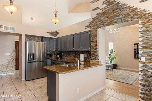 9141 E Bell Cactus Ln, Tucson, AZ 85715 - kitchen with stainless steel fridge, a sink, light tile patterned floors, a peninsula, and a high ceiling