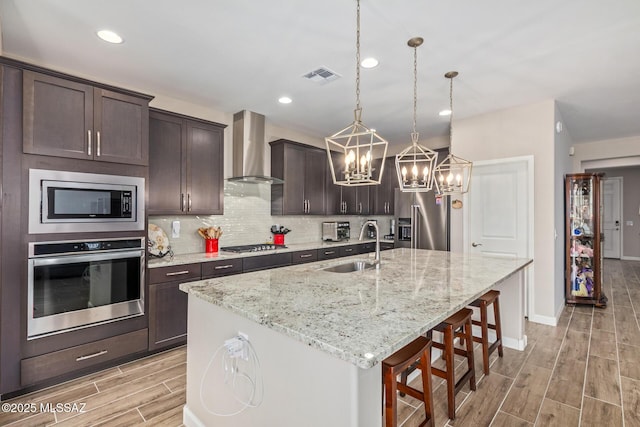 11815 N Silverscape Dr, Oro Valley, AZ 85737 - kitchen with stainless steel appliances, wall chimney exhaust hood, a sink, wood tiled floors, and a chandelier