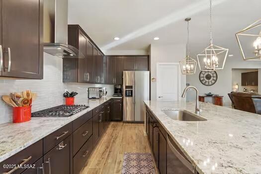 11815 N Silverscape Dr, Oro Valley, AZ 85737 - kitchen featuring appliances with stainless steel finishes, a sink, wall chimney range hood, dark brown cabinets, and light stone countertops