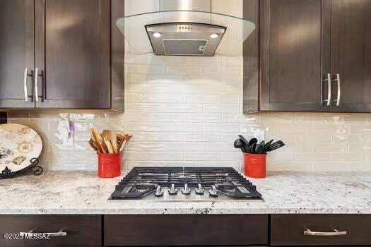 11815 N Silverscape Dr, Oro Valley, AZ 85737 - kitchen with exhaust hood, dark brown cabinetry, stainless steel gas cooktop, and light stone counters