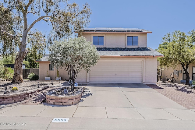 9650 N Gyor Pl, Tucson, AZ 85742 - view of front of home featuring driveway, an attached garage, stucco siding, and roof mounted solar panels