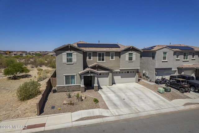 5550 S Sycamore Rim Trl, Tucson, AZ 85747 - view of front of home featuring an attached garage, stucco siding, roof mounted solar panels, and driveway