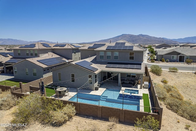 5550 S Sycamore Rim Trl, Tucson, AZ 85747 - back of house with a fenced backyard, roof mounted solar panels, a pool with connected hot tub, a mountain view, and a residential view
