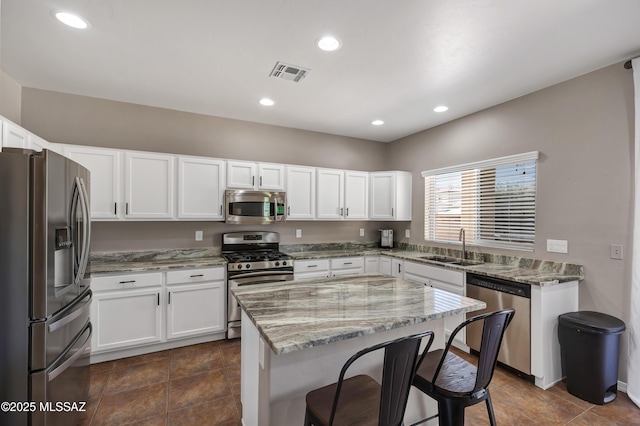 19 W Via Teresita, Sahuarita, AZ 85629 - kitchen with stainless steel appliances, a sink, light stone countertops, a breakfast bar, and white cabinets