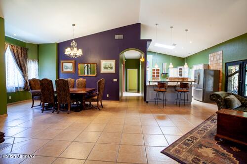 480 Camino Ramanote, Rio Rico, AZ 85648 - dining area featuring arched walkways, vaulted ceiling, light tile patterned floors, a chandelier, and plenty of natural light