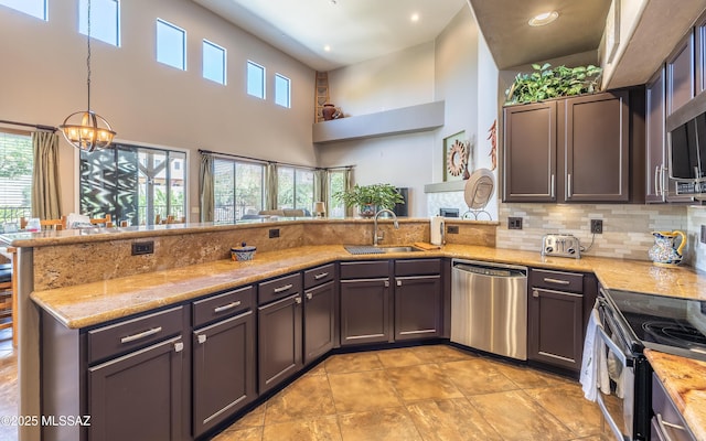 9387 S Via Famero, Vail, AZ 85641 - kitchen featuring appliances with stainless steel finishes, a sink, light stone counters, a peninsula, and tasteful backsplash
