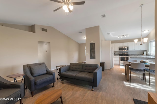 11561 N Eagle Peak Dr, Oro Valley, AZ 85737 - living area with lofted ceiling, ceiling fan, light wood-style floors, baseboards, and a chandelier