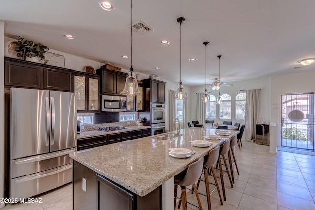 9978 N Niobrara Way, Tucson, AZ 85742 - kitchen with appliances with stainless steel finishes, a large island, dark brown cabinets, a breakfast bar, and ceiling fan