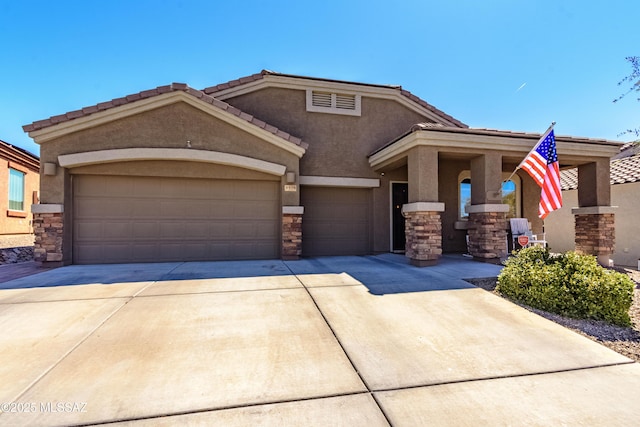 9978 N Niobrara Way, Tucson, AZ 85742 - view of front of home with stone siding, driveway, a garage, stucco siding, and a tiled roof