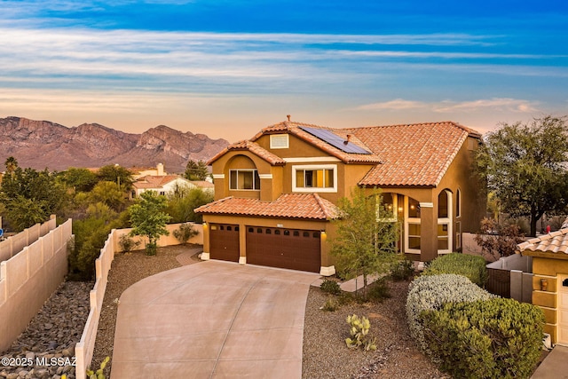 11262 N Chynna Rose Pl, Oro Valley, AZ 85737 - mediterranean / spanish house featuring concrete driveway, a tiled roof, a mountain view, roof mounted solar panels, and stucco siding