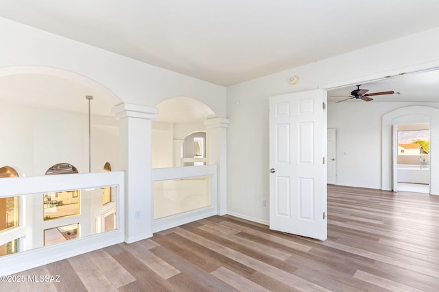 11262 N Chynna Rose Pl, Oro Valley, AZ 85737 - unfurnished room with arched walkways, wood finished floors, a ceiling fan, decorative columns, and baseboards