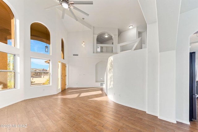 11262 N Chynna Rose Pl, Oro Valley, AZ 85737 - unfurnished living room featuring a ceiling fan, a high ceiling, wood finished floors, and arched walkways